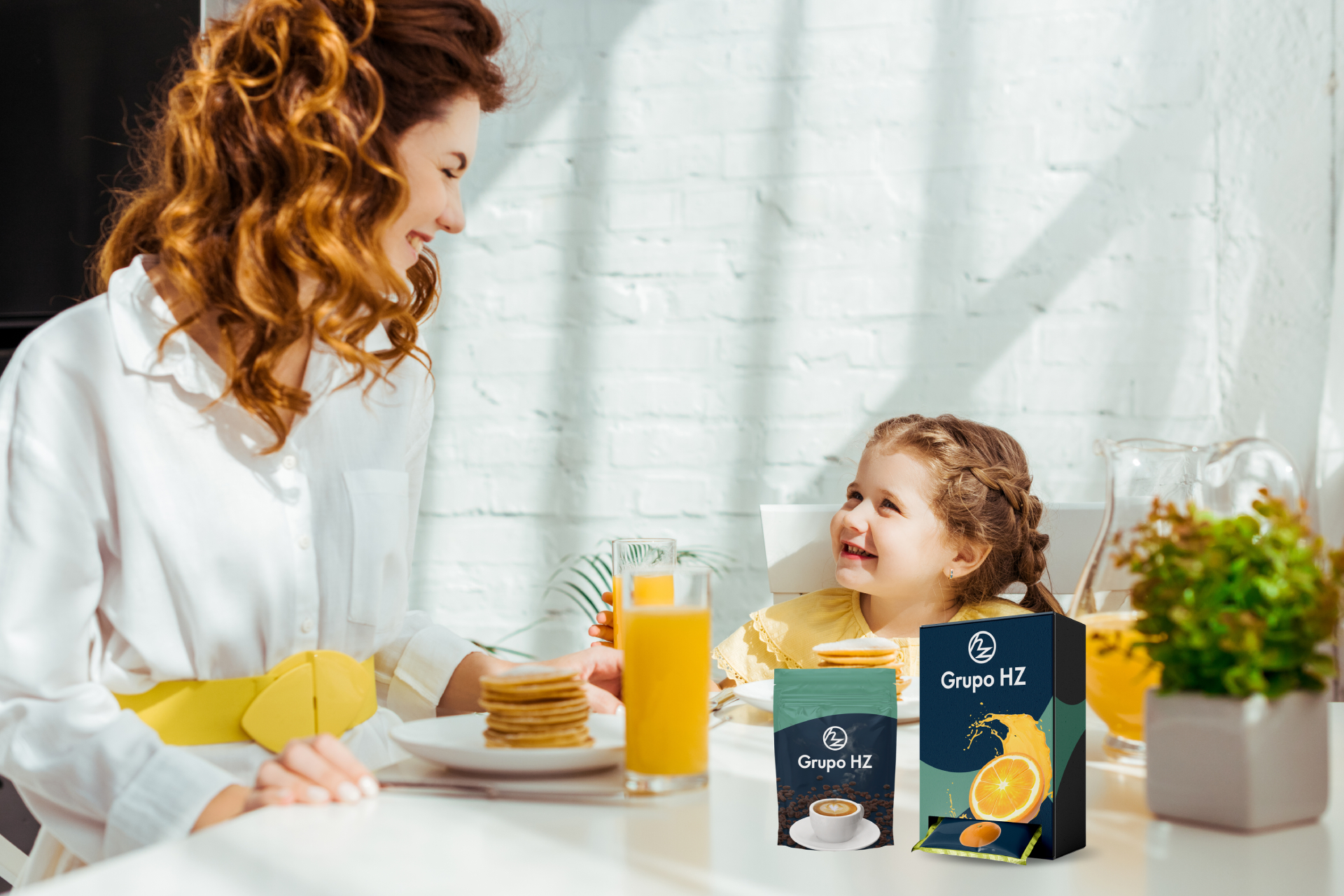 En la imagen se muestra una señora y su hija desayunando y hay dos envoltorios de grupohz de cafe y naranja.